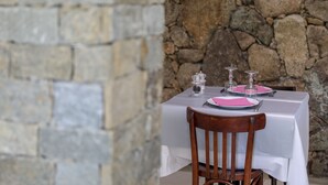 A table set with pink napkins, plates, and clear glassware against a stone wall backdrop. - Hotel Macchie E Fiori (Pianotolli-Caldarello)