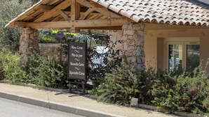 A rustic stone building with a tiled roof, a signboard listing menu items, and a bench in front. - Hotel Macchie E Fiori (Pianotolli-Caldarello)