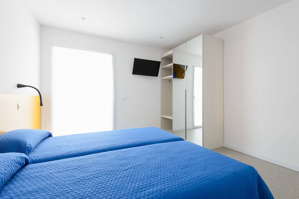A bedroom with a bed, a TV, a wardrobe, and a door.