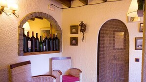 A cozy interior with wicker chairs, a small table, and a wall-mounted wine rack. - Hostal El Bouquet (La Vall de Boi)