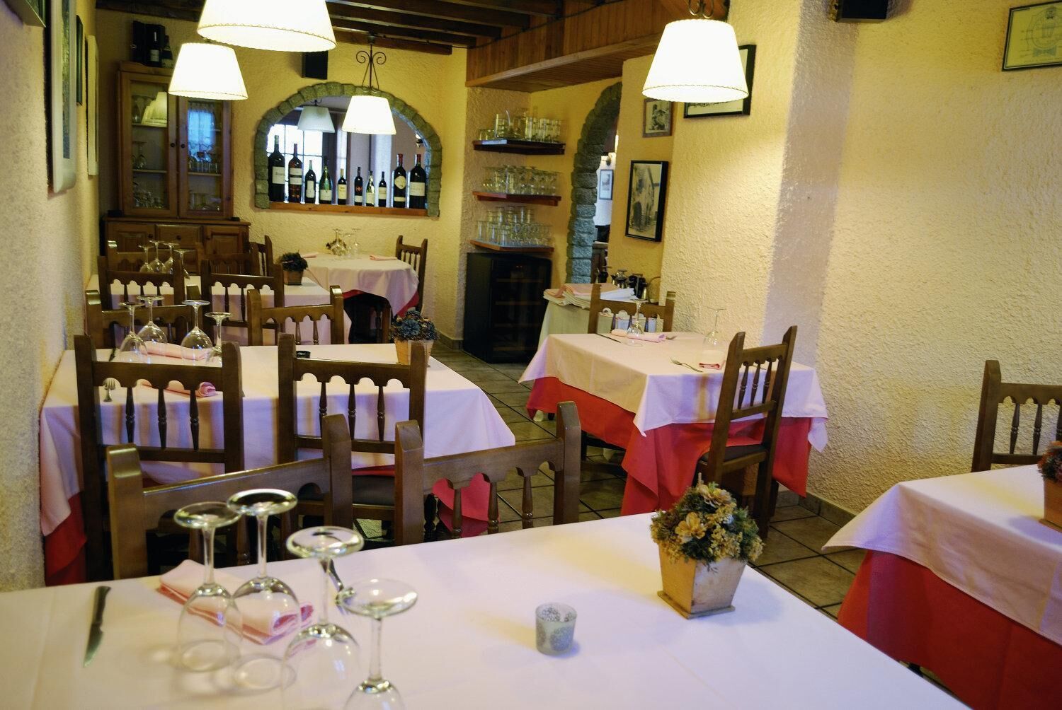 Un restaurante con varias mesas, cada una con copas de vino y cubiertos.