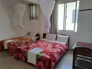 A room with two single beds, a desk, and a chair.