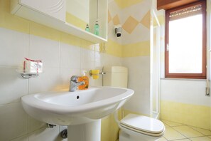 A bathroom with a white sink, toilet, and yellow and white tiled walls.