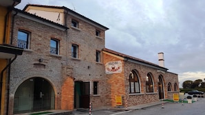 Un bâtiment à deux étages, construit en briques, avec une enseigne indiquant « Al Pajoolo » et une cheminée.