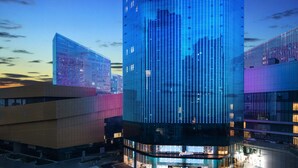A modern hotel with a distinctive illuminated facade, a central entrance, and a well-maintained surrounding area. - Radisson Ningbo Beilun (Ningbo)