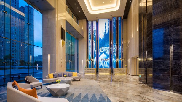 A modern lobby with a seating area, large windows, and a digital forest display. - Radisson Ningbo Beilun (Ningbo)