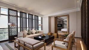 A modern living room with a sofa, coffee table, and chairs, large windows, and a view of the city. - Radisson Ningbo Beilun (Ningbo)