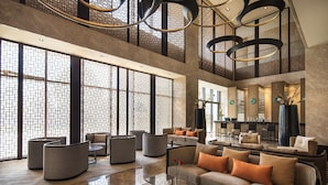 Eine großzügige Lobby mit hohen Decken, großen Fenstern und zeitgemäßen Möbeln.