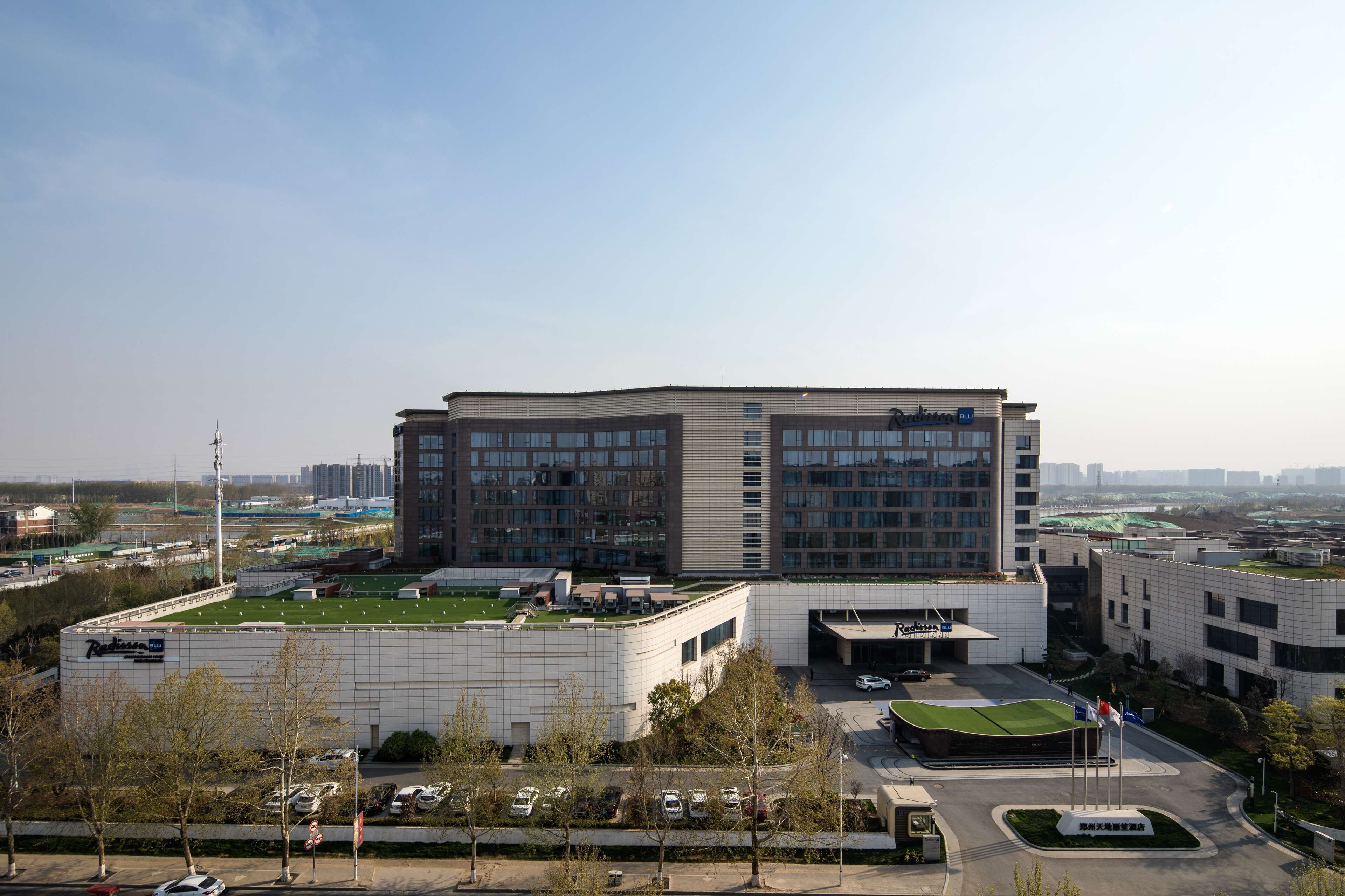 A modern building with a flat roof, multiple windows, and a parking area.