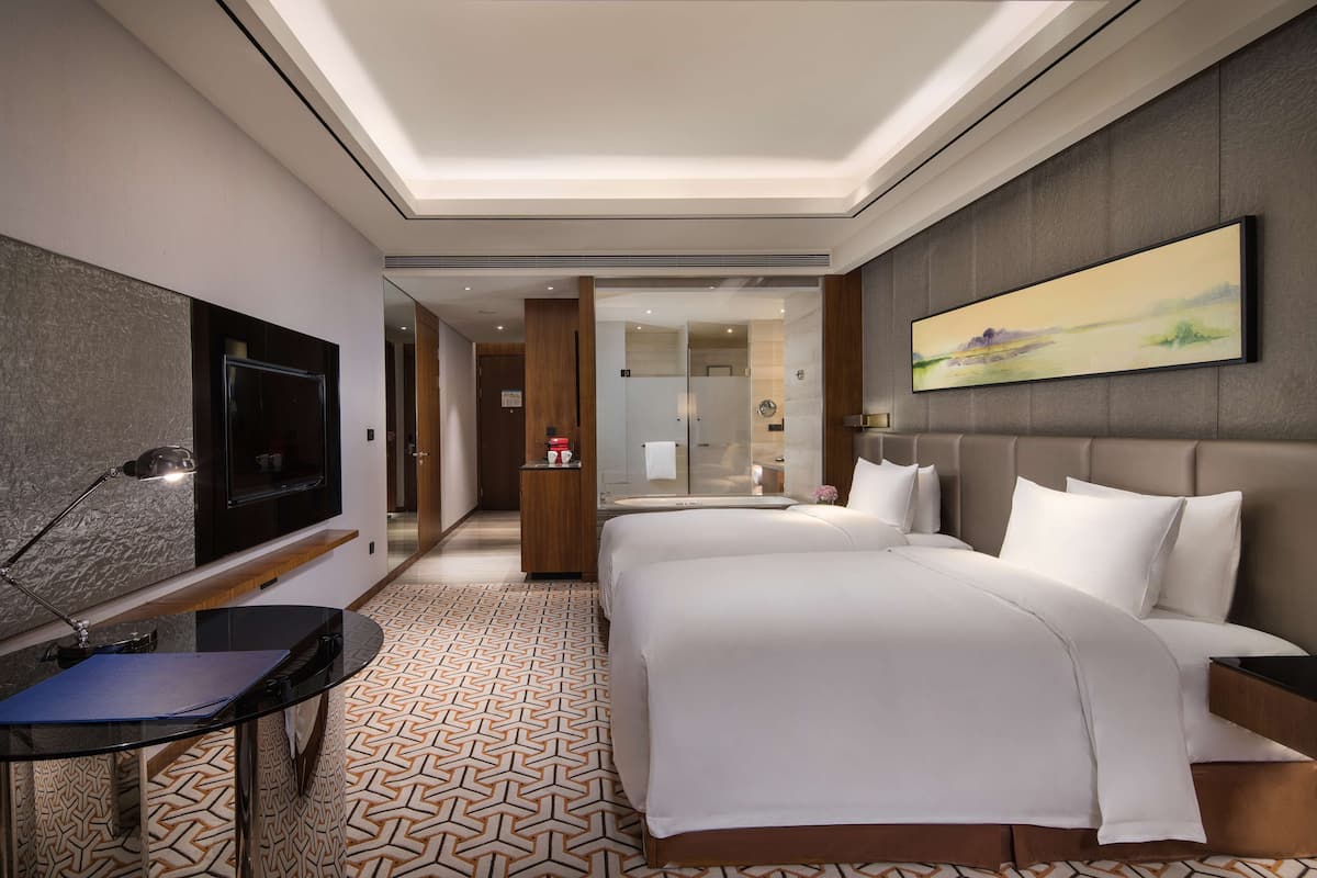 Een hotelkamer met een groot bed, een bureau met een computer, een televisie en een schilderij aan de muur.