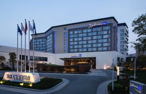 Un hôtel Radisson Blu à l’architecture moderne, avec plusieurs enseignes et une entrée bien éclairée.