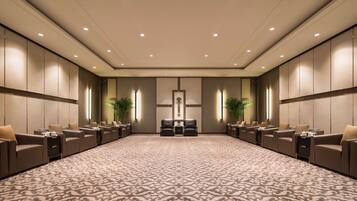 A spacious conference room with a patterned carpet, leather seating, and wall-mounted lighting.