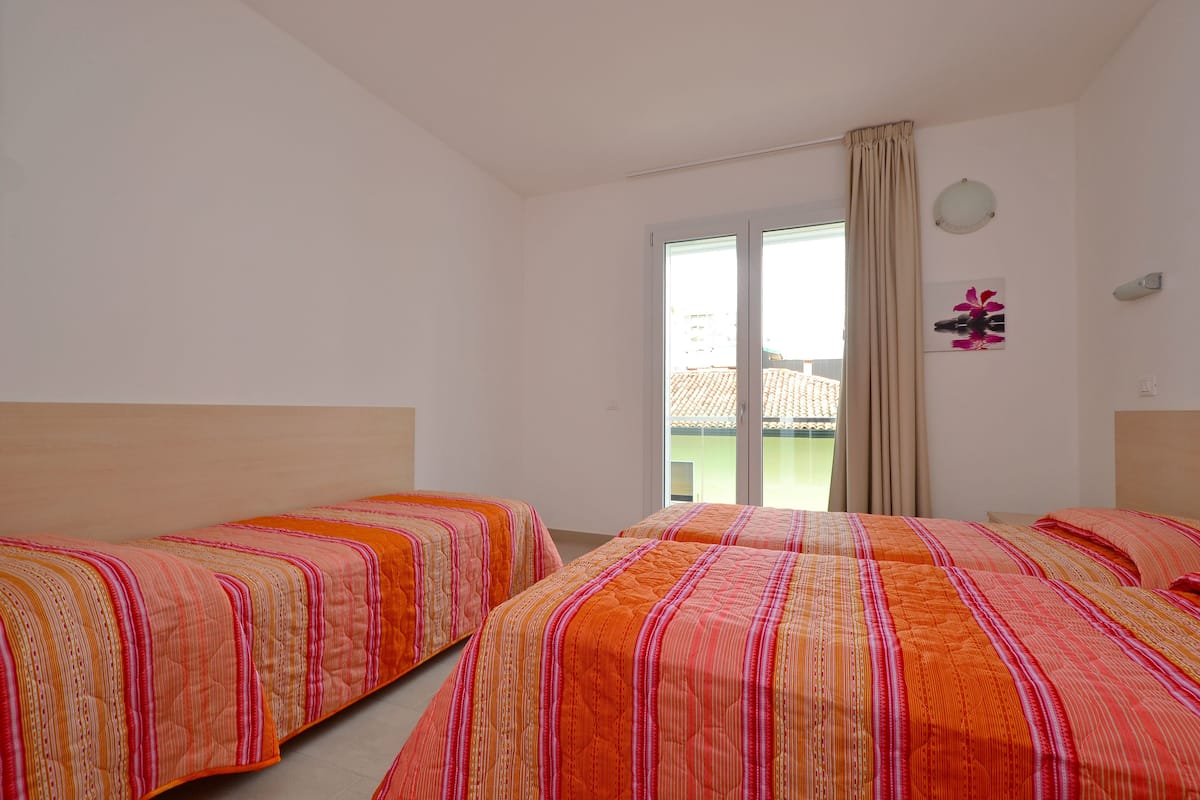 Habitación de hotel con dos camas, un ventanal con vistas a edificios y una cortina.