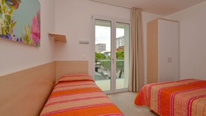 Een hotelkamer met twee bedden, een schuifdeur naar buiten, een kledingkast en een schilderij aan de muur.