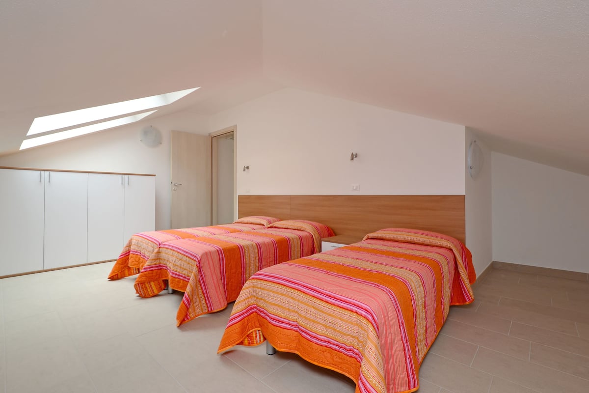 Un dormitorio con dos camas, un tragaluz y un cabecero de madera.
