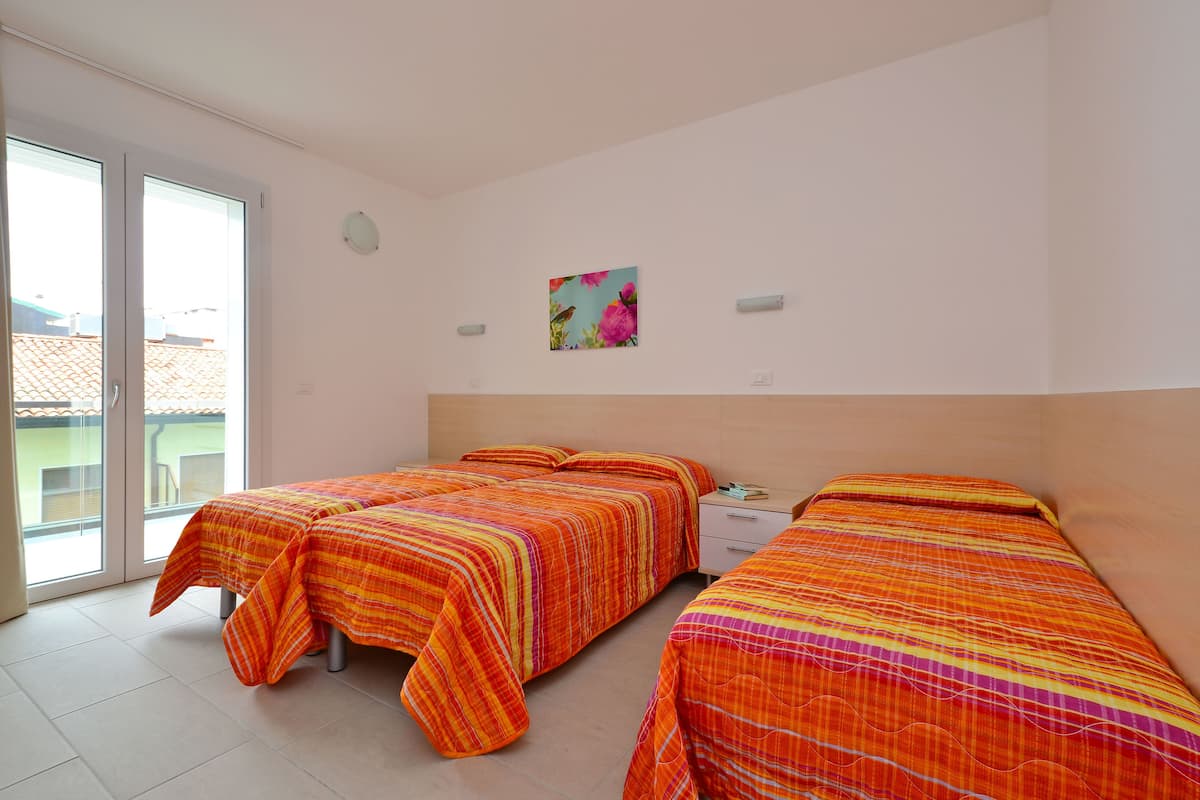 Un dormitorio con dos camas, una mesita de noche pequeña y una ventana.