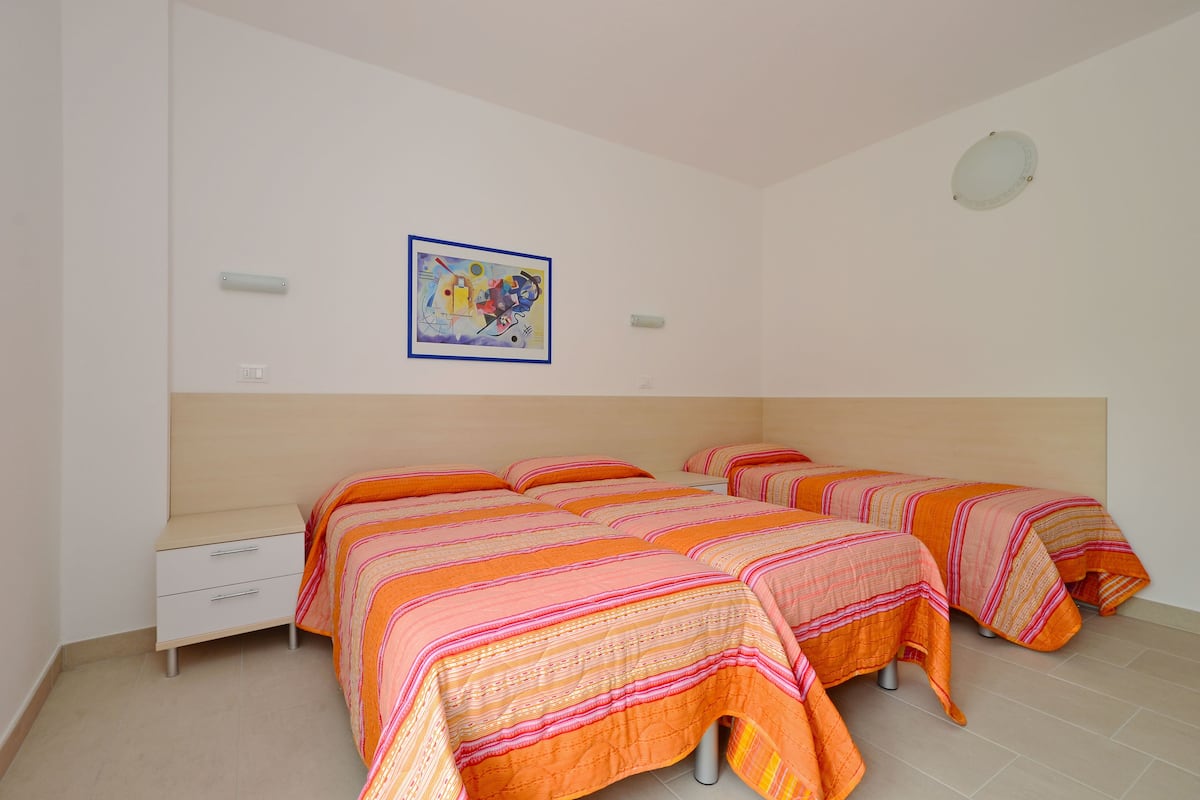 Habitación con dos camas, una mesita de noche, una lámpara de pared y un aplique de techo.