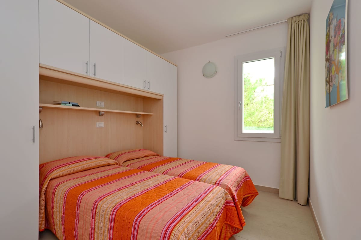 Un dormitorio con dos camas, una ventana con cortinas y un reloj de pared.