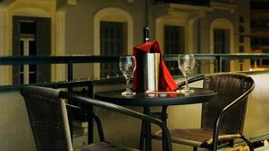 Ein Tisch mit zwei Stühlen, einer roten Servietten, einer silbernen Flasche und zwei Weingläsern.