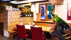 Un coin repas avec une table en bois, des chaises rouges et un meuble à vin contenant des bouteilles.