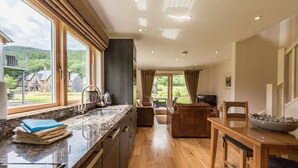 Une cuisine moderne dotée d’une grande fenêtre, d’un plancher en bois et d’un coin repas avec une table et des chaises.