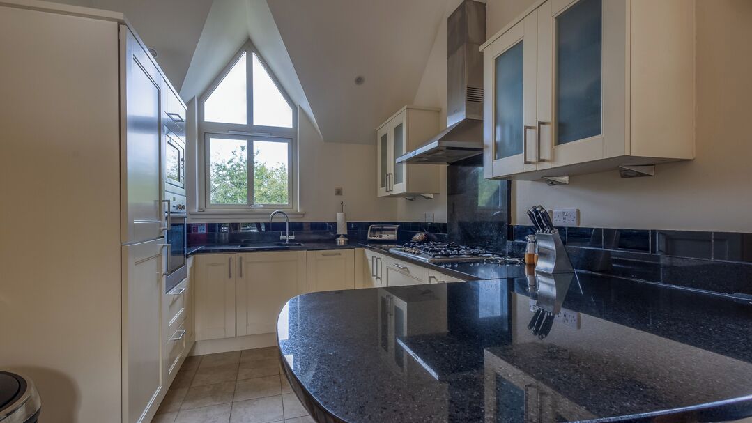 A kitchen with a large island, white cabinets, and a window providing natural light.