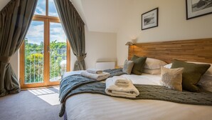Une chambre avec un grand lit, une tête de lit en bois et une vue sur la verdure grâce à une porte coulissante.