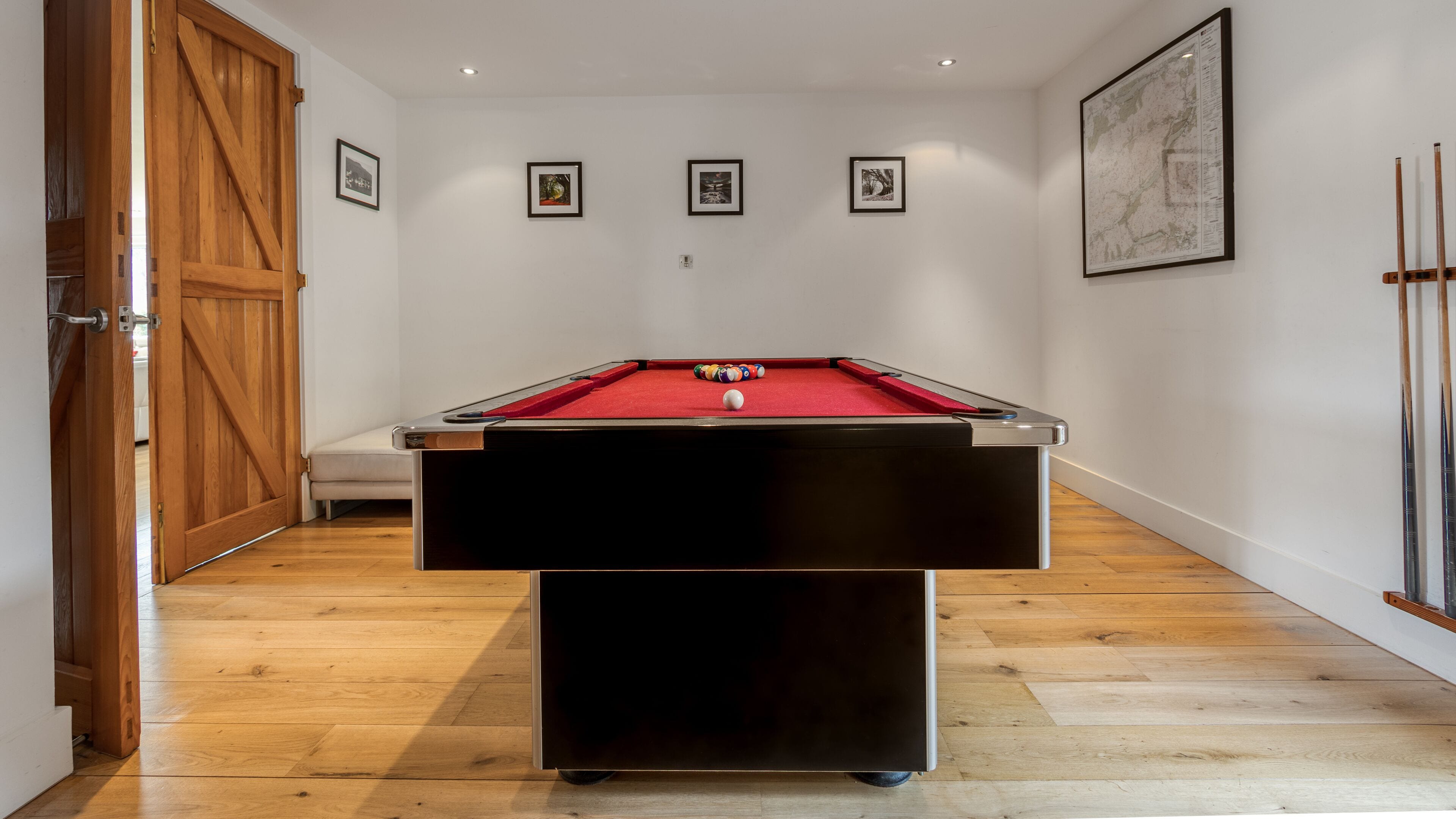 Une table de billard dans une pièce dont le sol est en bois et les murs sont blancs.
