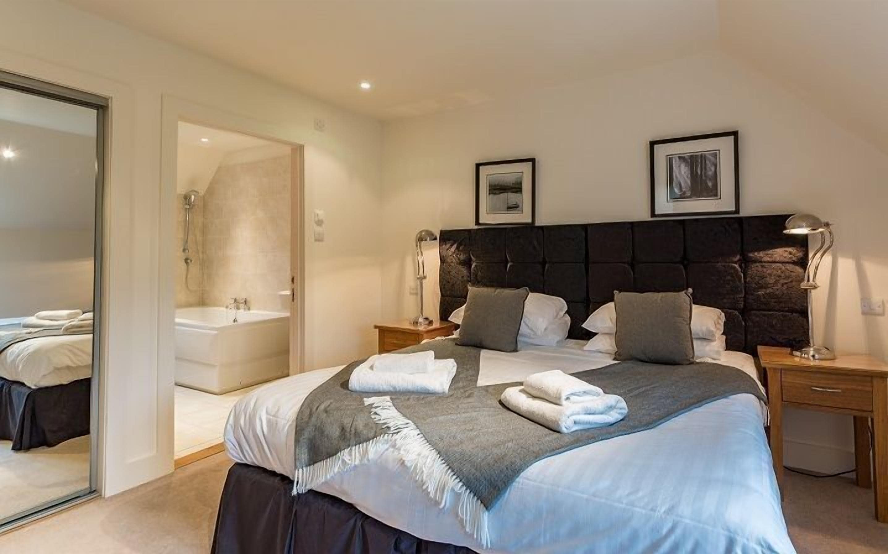 Une chambre à coucher moderne avec un grand lit, une salle de bain séparée et deux tableaux encadrés accrochés au mur.