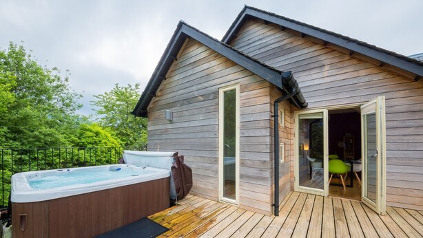 Une cabane en bois avec un jacuzzi et une terrasse.