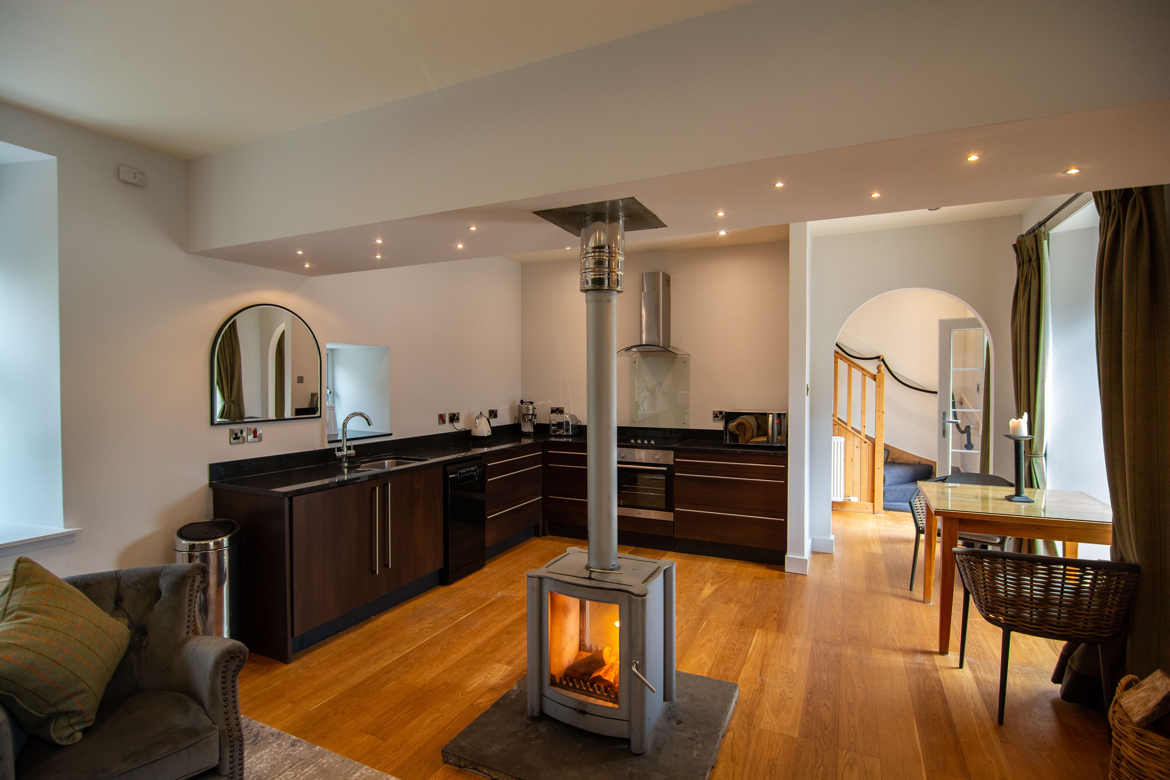 Een moderne keuken met donkere kastjes, een centraal eiland en een houtkachel.