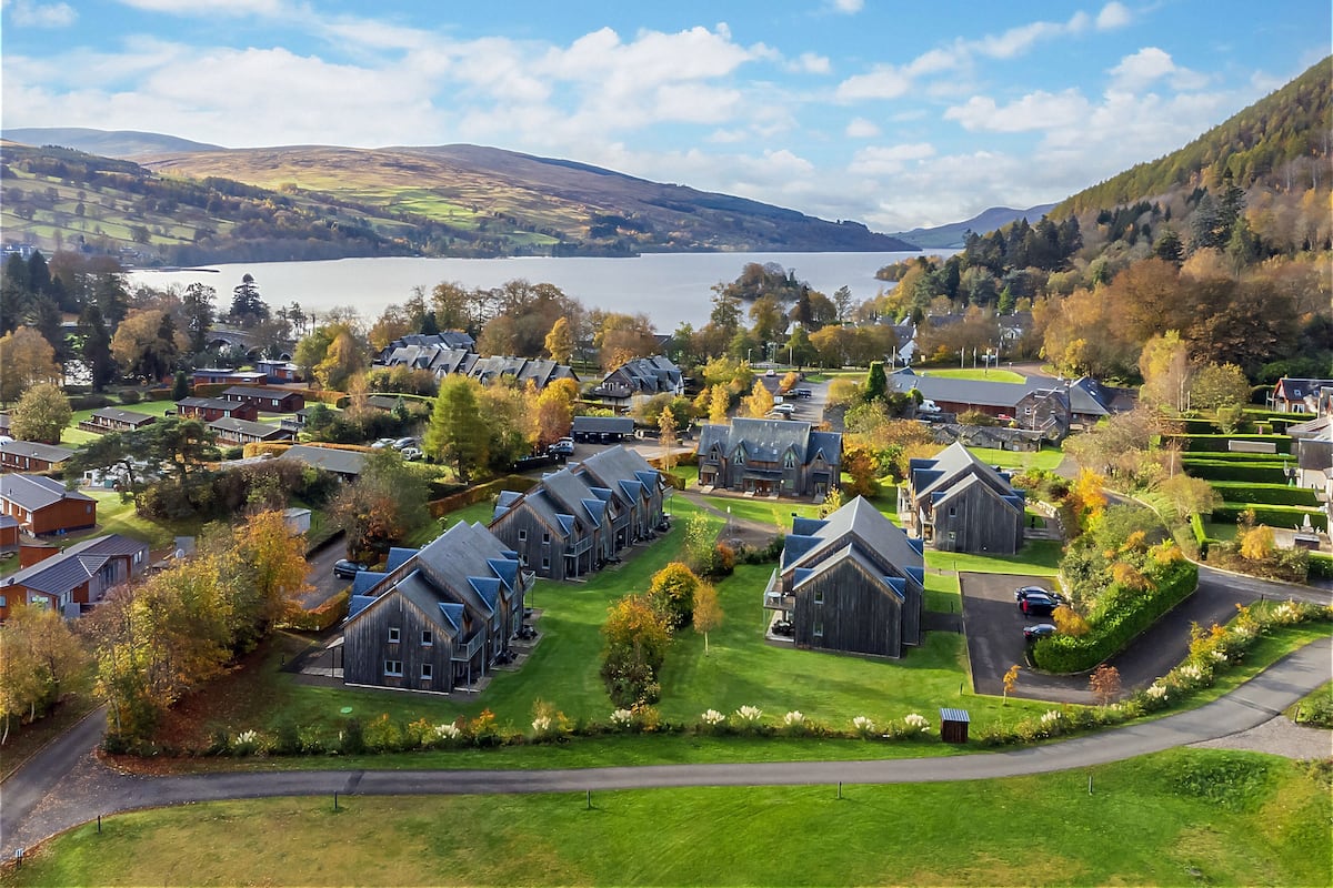 Un quartier résidentiel avec des maisons, un lac et des collines en arrière-plan.