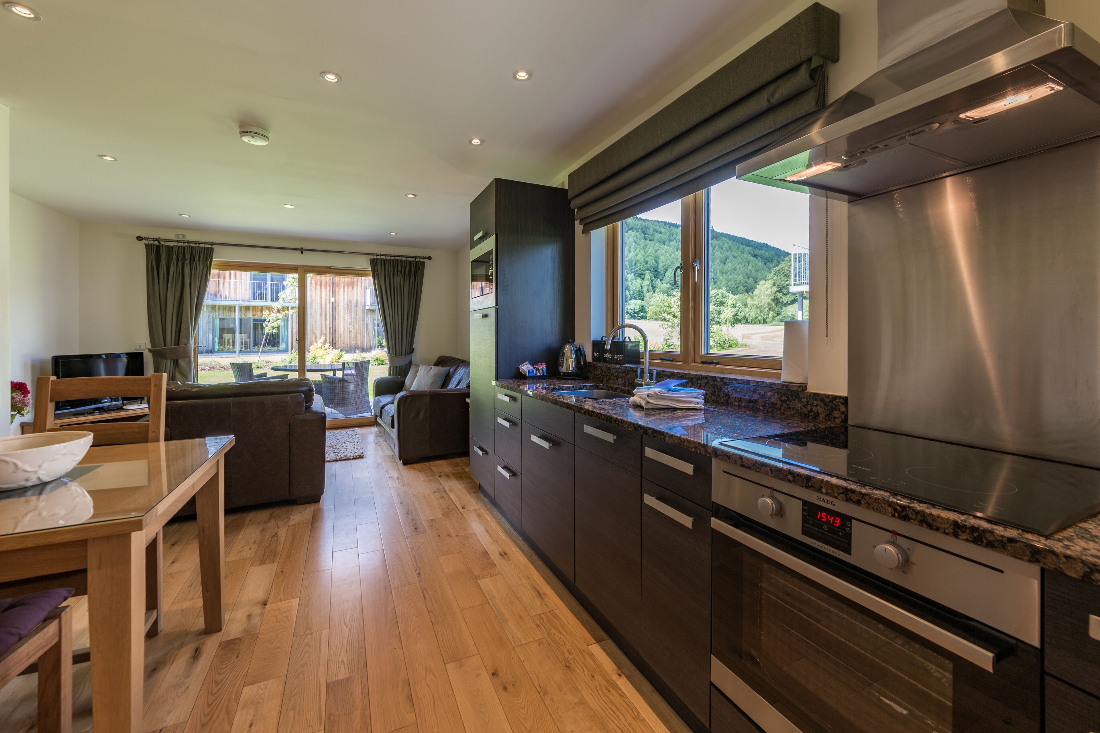 A modern kitchen with a stainless steel range hood, wooden cabinets, and a built-in oven.