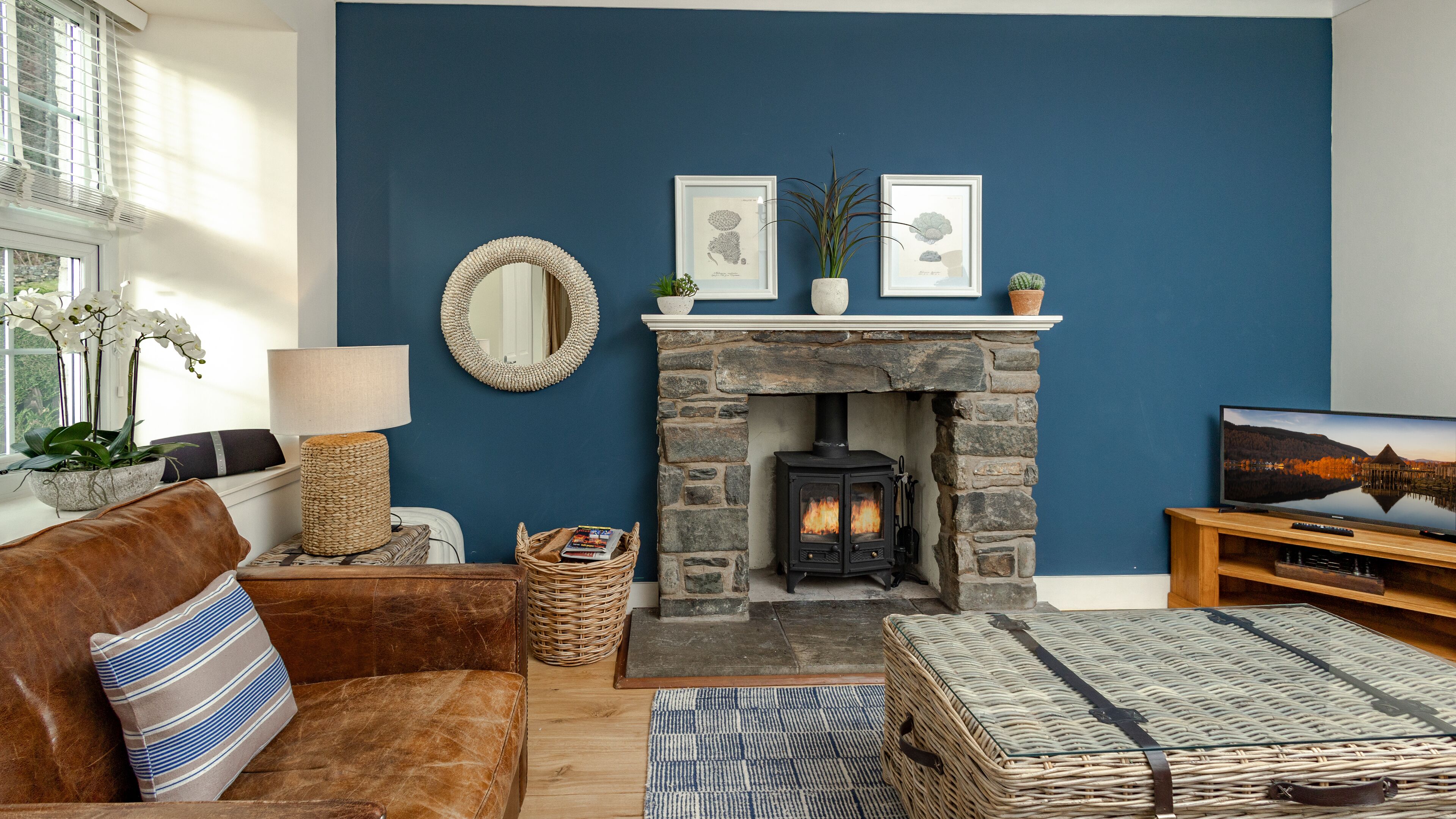 Una sala de estar acogedora con chimenea de piedra, un sofá cómodo, un televisor y objetos decorativos en la repisa.