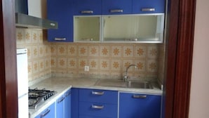 A compact kitchen with blue cabinets, a gas stove, and a sink.