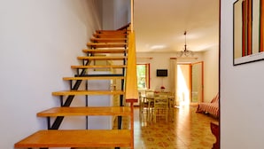 A staircase with wooden steps and black metal railings leading to a dining area with a table and chairs.