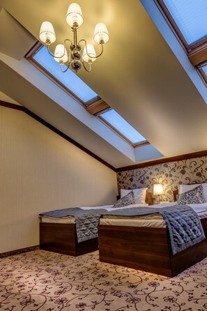 Une chambre avec un puits de lumière, un lit avec une tête de lit et un lustre.
