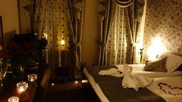 A hotel room with a bed, a desk with a vase of flowers, and curtains.
