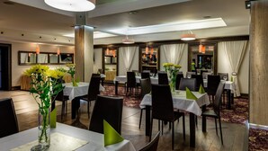 A hotel dining area with multiple tables, chairs, and a bar area.