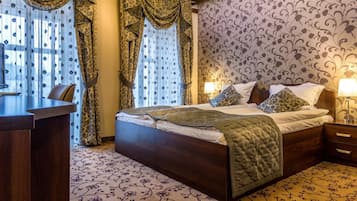 A hotel room with a large bed, a desk, and a patterned carpet.