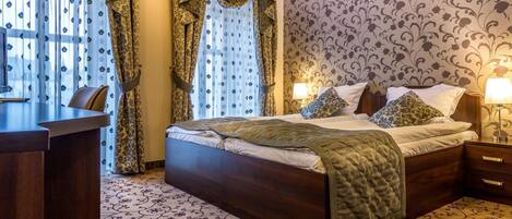 Une chambre d’hôtel avec un grand lit, un bureau et une moquette à motifs.