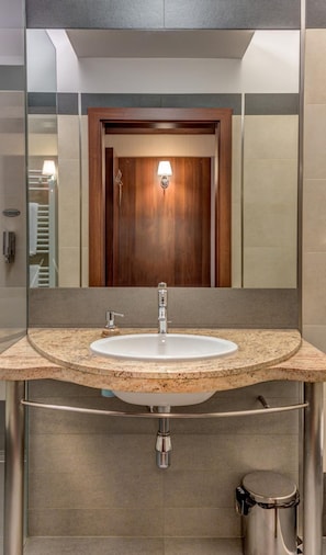 A bathroom with a round sink, a mirror, and a wooden door. - Hotel-restauracja Platan (Chrzanow)
