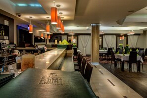 A restaurant interior with a bar area, dining tables, and hanging pendant lights. - Hotel-restauracja Platan (Chrzanow)