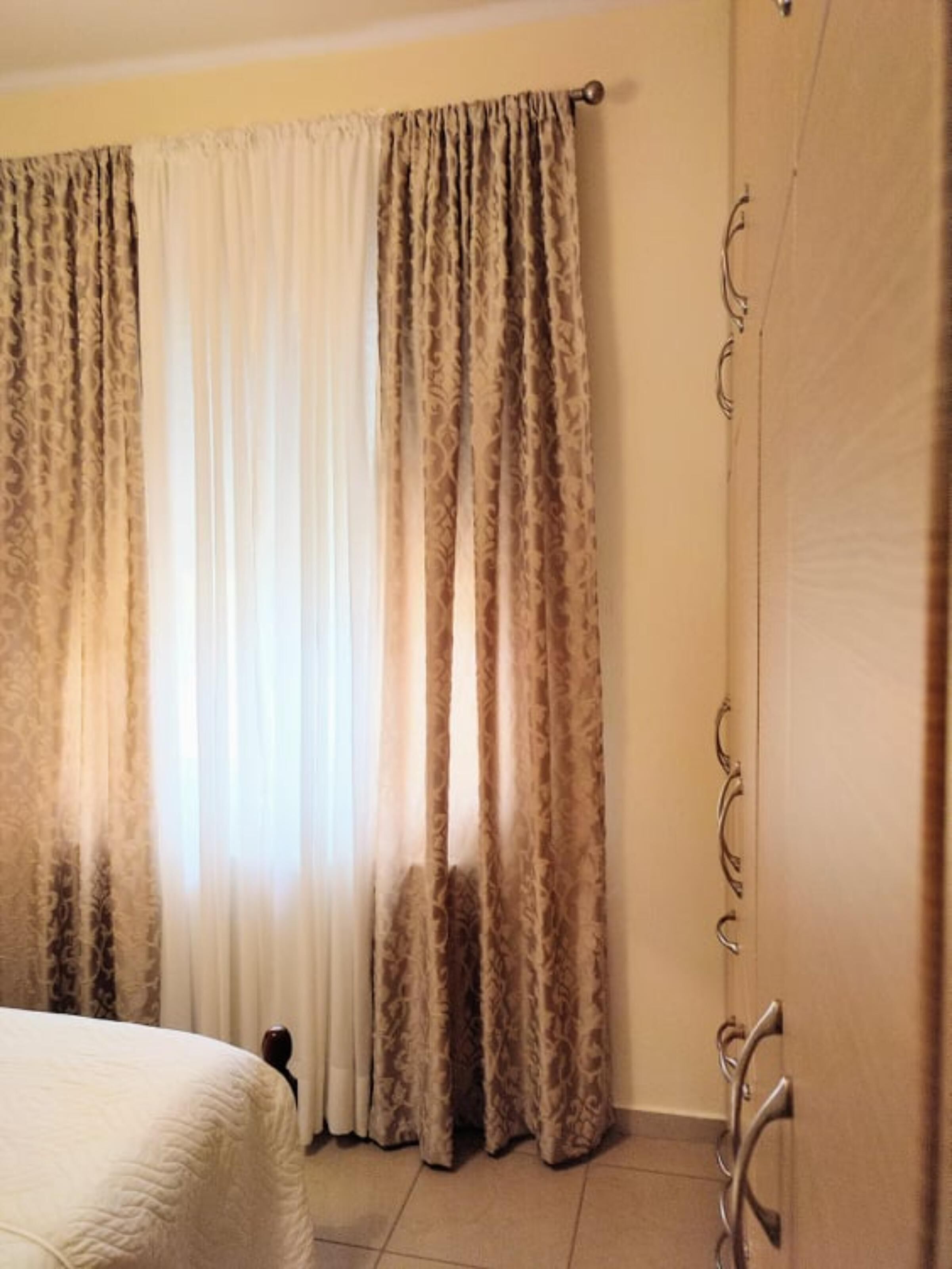 A bedroom with a bed, curtains, and a door with a handle.