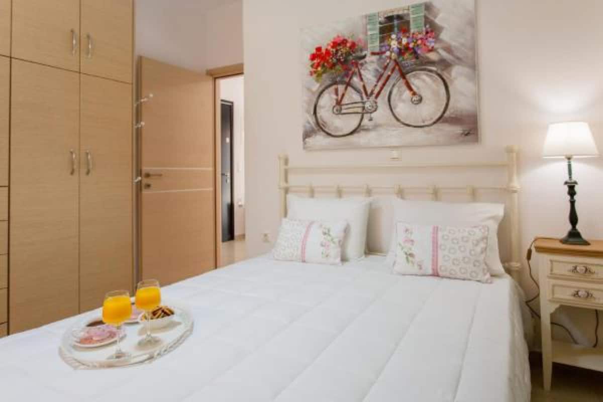 Une chambre d’hôtel avec un lit, une table de chevet, une lampe, un tableau représentant un vélo et un plateau avec des articles pour le petit-déjeuner.