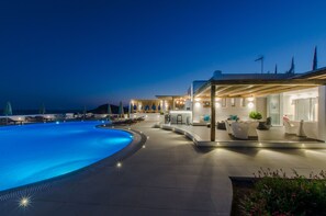 A modern hotel with a swimming pool, outdoor seating, and a bar area. - Lianos Village (Naxos)