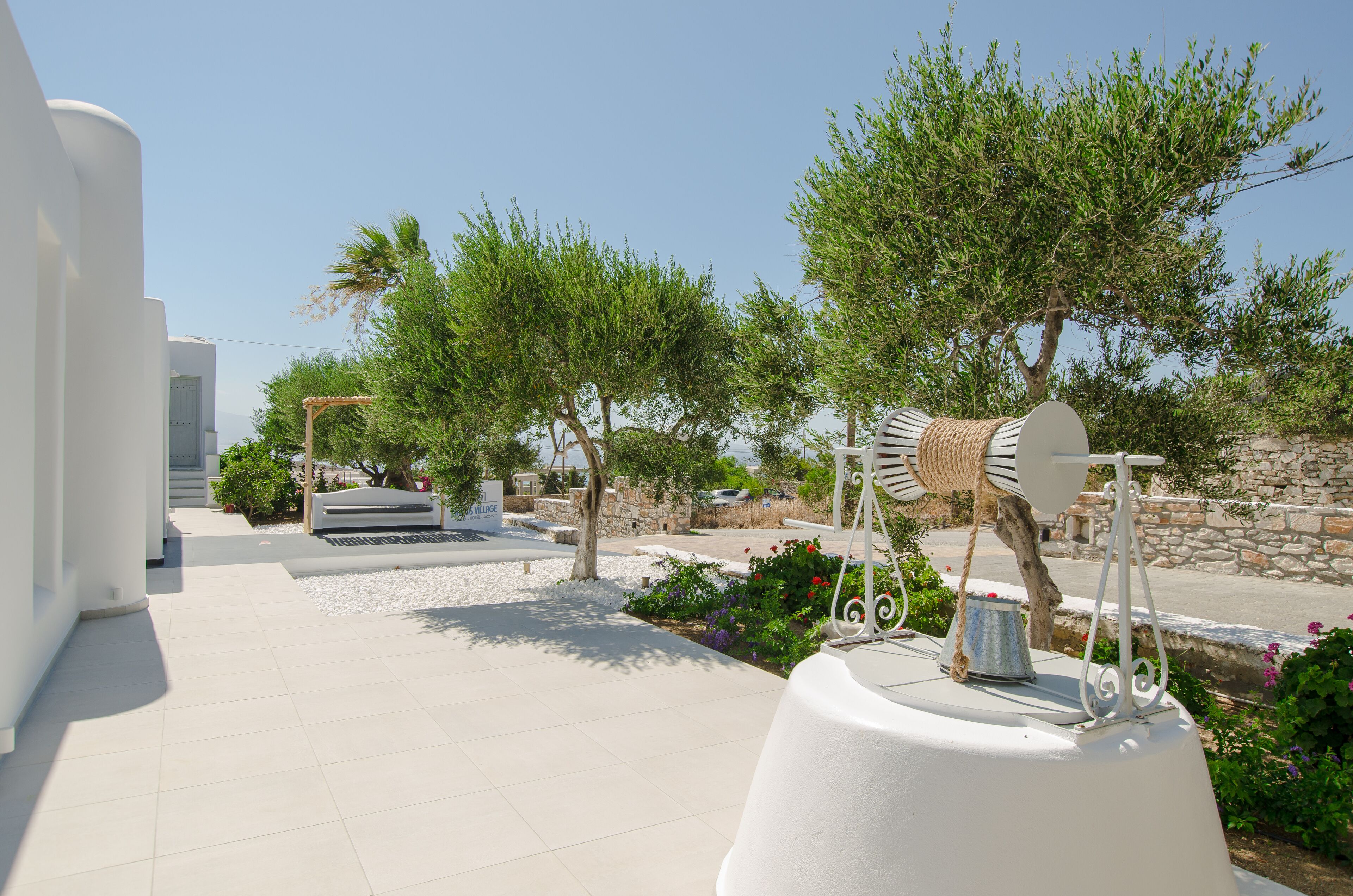 A modern outdoor area with a white building, a pathway, and a decorative metal sculpture.