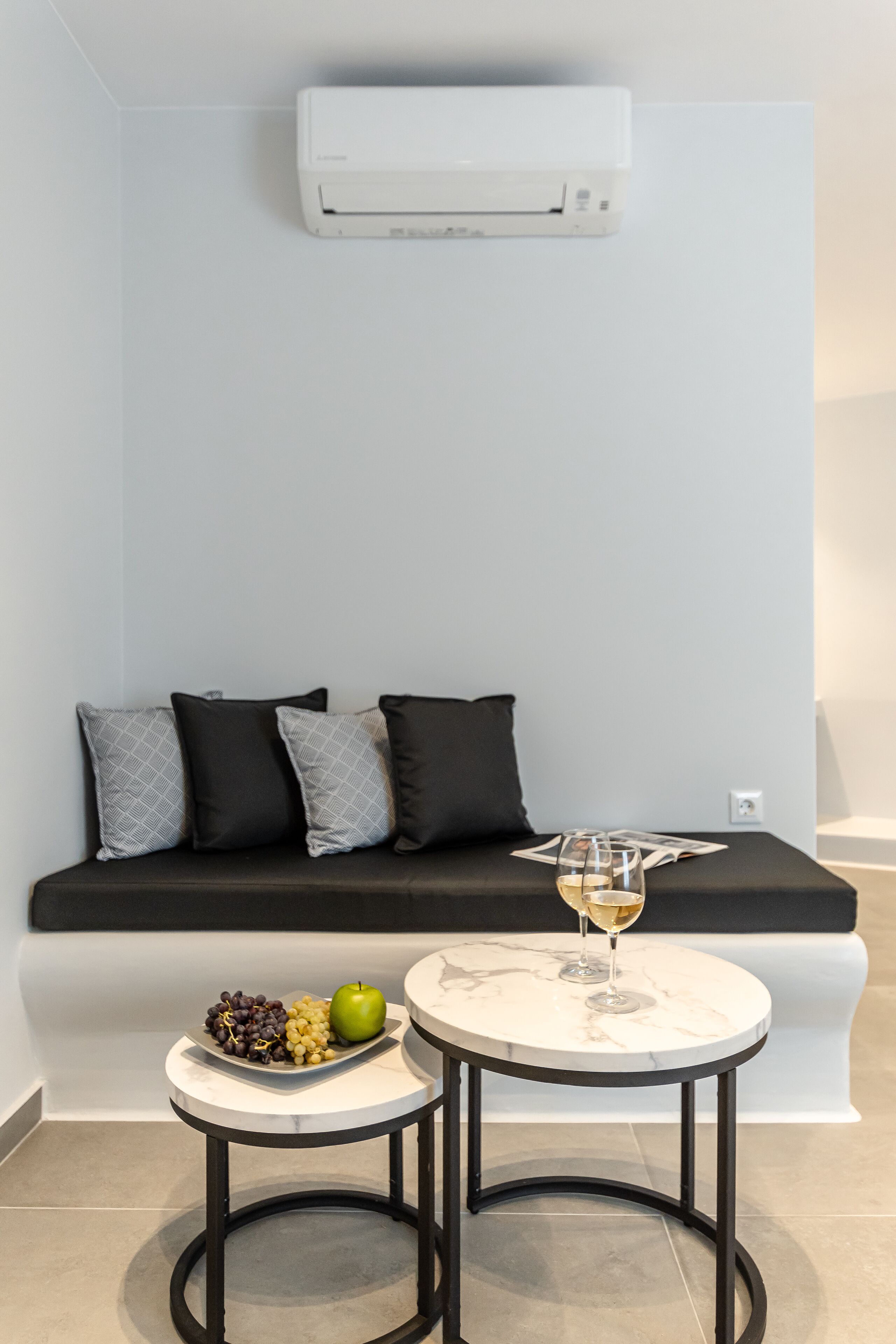 A modern living area with a sofa, a small round table, and a wall-mounted air conditioner.