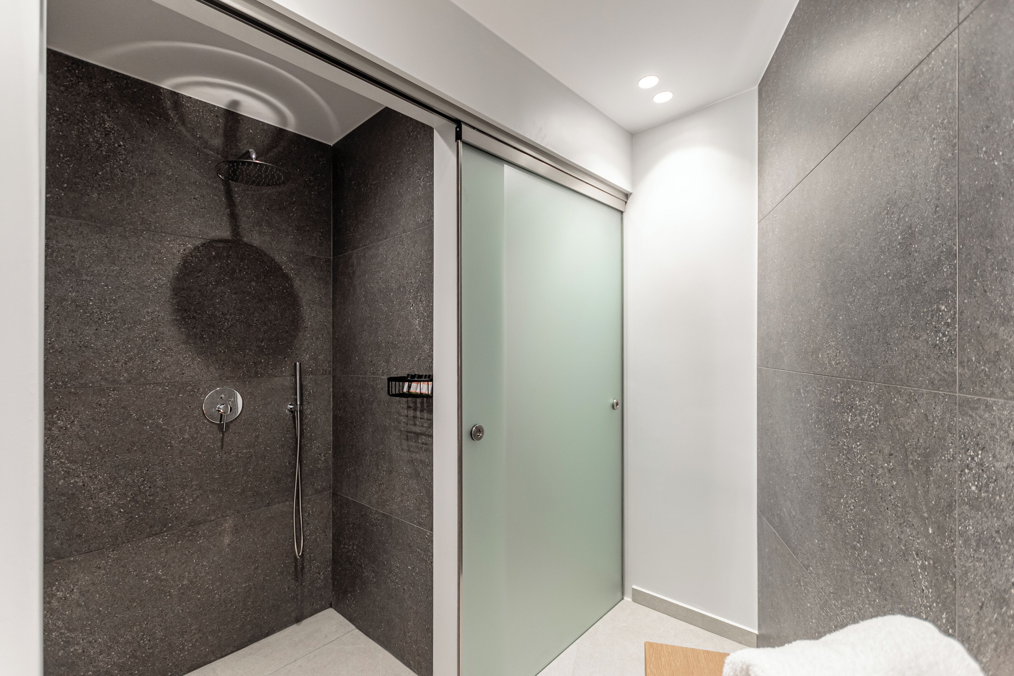 A modern bathroom with a glass shower enclosure, a walk-in shower, and a glass door.