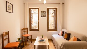 A cozy room with a bed, a table, two chairs, and two windows with stone walls. - Daliani Studios Chania (Chania)